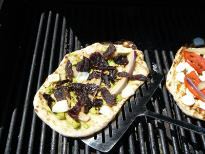 Moving grilled pizza with wide fish spatula